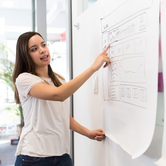 Woman pointing to whiteboard graph in a presentation
